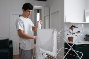 Young student hanging his washing on clothes dryer
