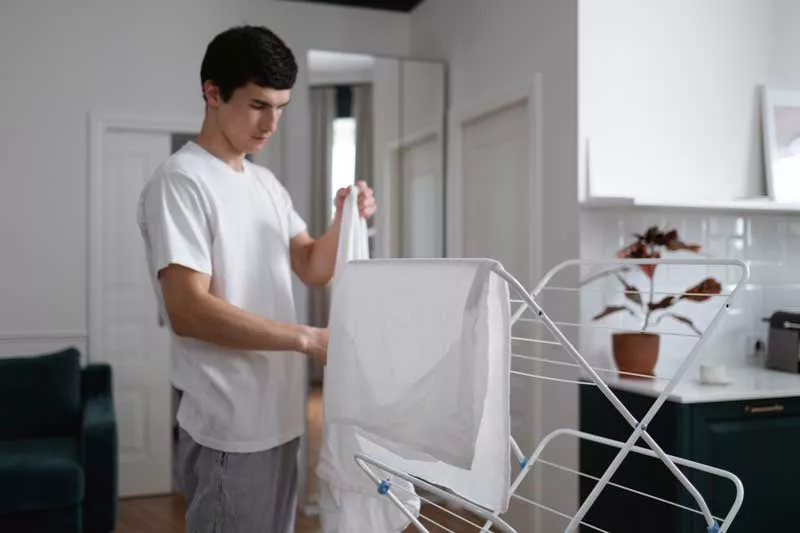 Young student hanging his washing on clothes dryer